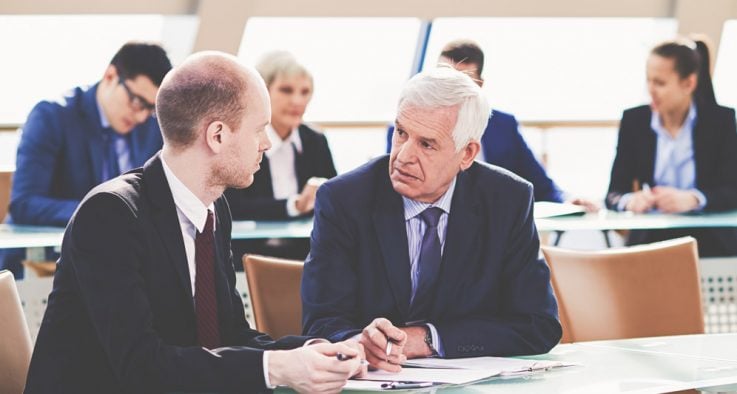 Two government workers discuss an issue at a table.