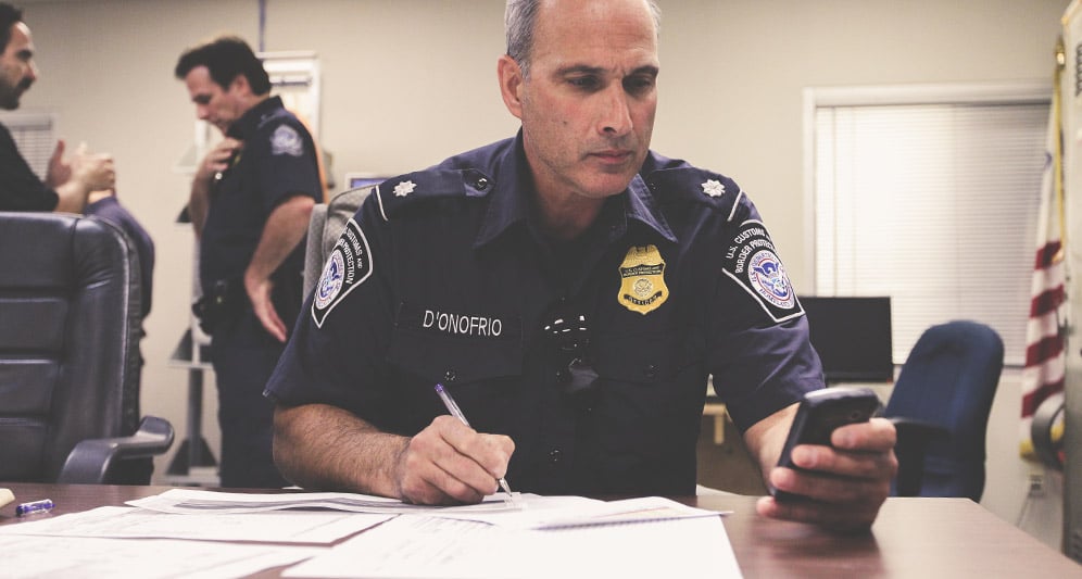 police officer with smartphone doing paperwork 