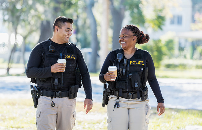 Two officers walking and holding coffee