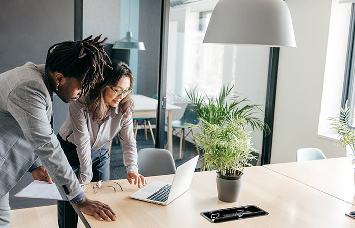 Two people looking at a laptop on a desk