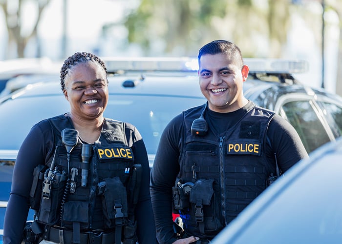 two-police-officers-smiling-outside-police-cars