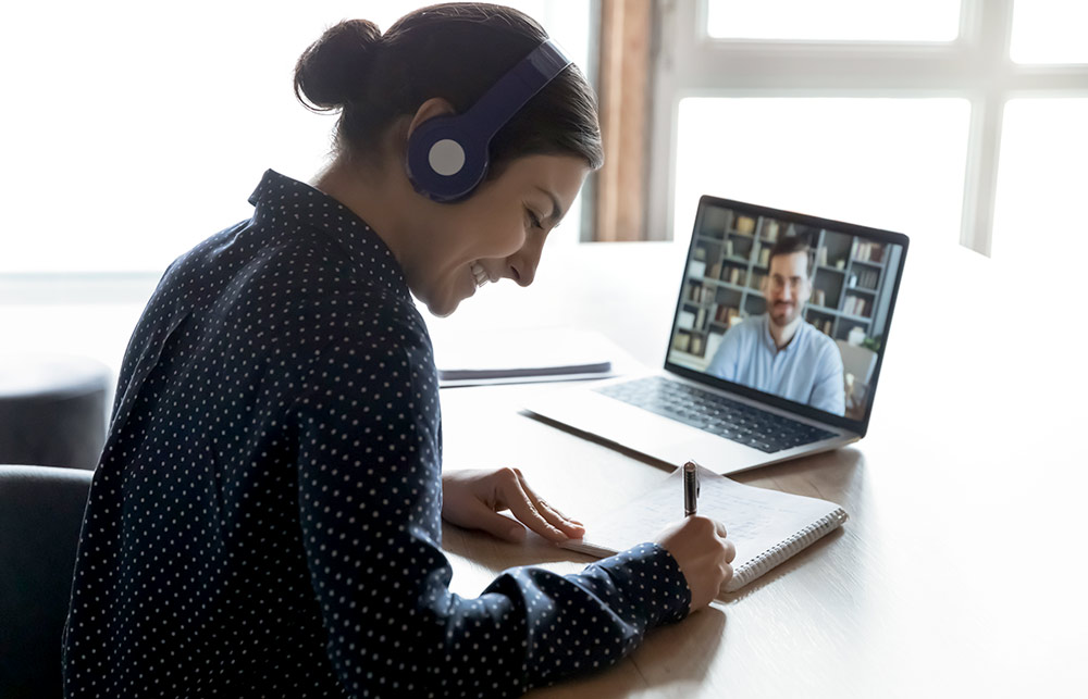 woman taking notes during online training