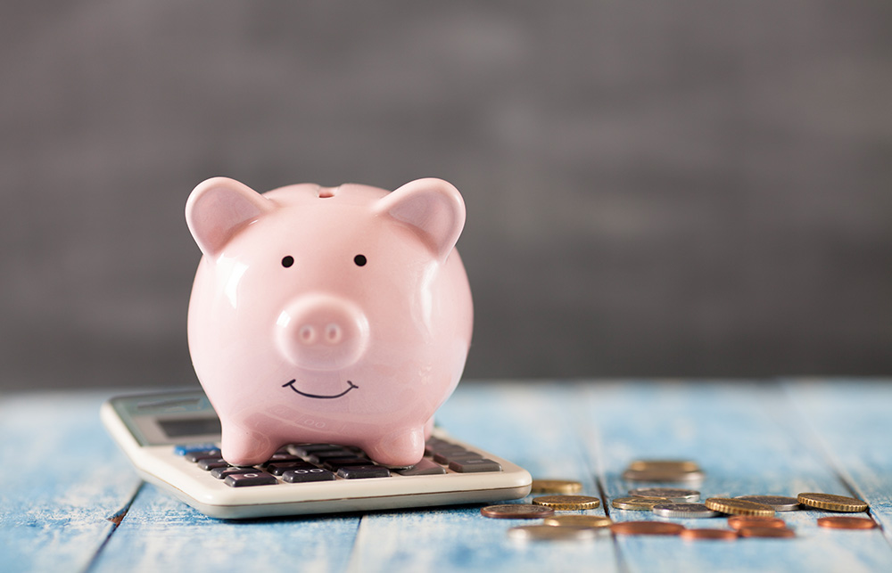 piggy bank on a calculator with change on the side