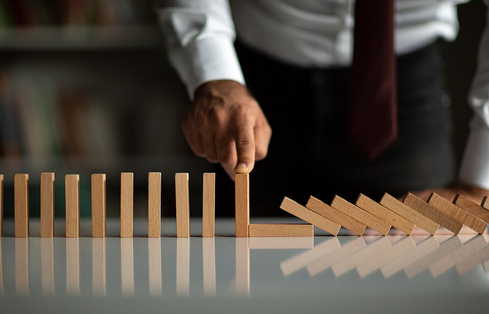 businessman with finger on domino