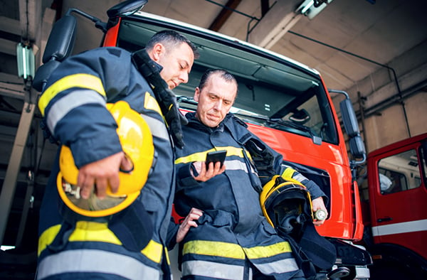 firemen looking at policies on smartphone